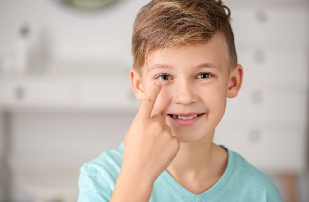 A young boy putting on a MiSight contact lens on his right eye.