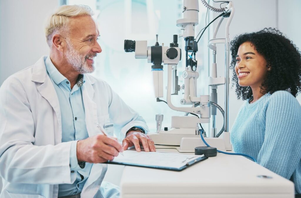 A male optometrist and a female patient smiling while discussing the results of an eye exam.