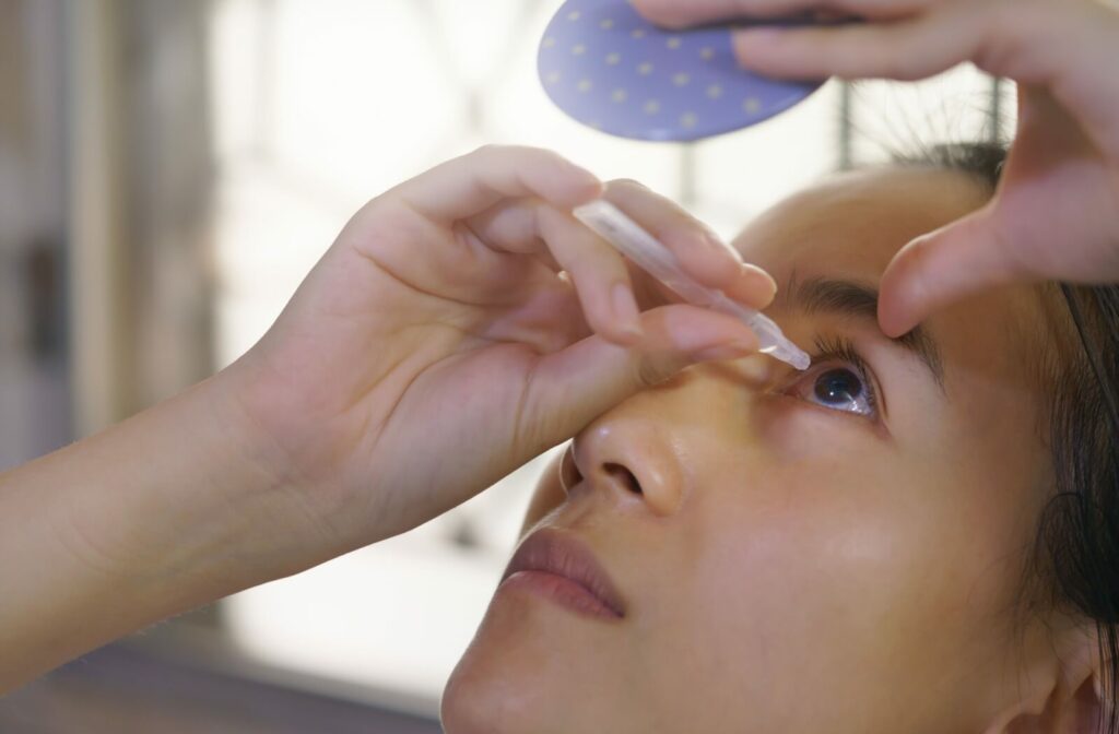 A close-up of a woman applying eye drops to relieve dryness and irritation.